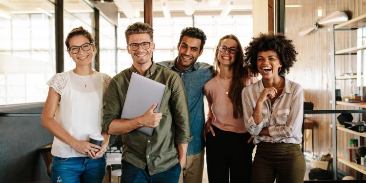Portrait of creative business team standing together and laughing. Multiracial business people together at startup.